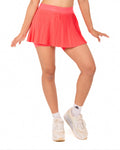 Woman wearing a white sleeveless top and pink pleated skirt on a white background